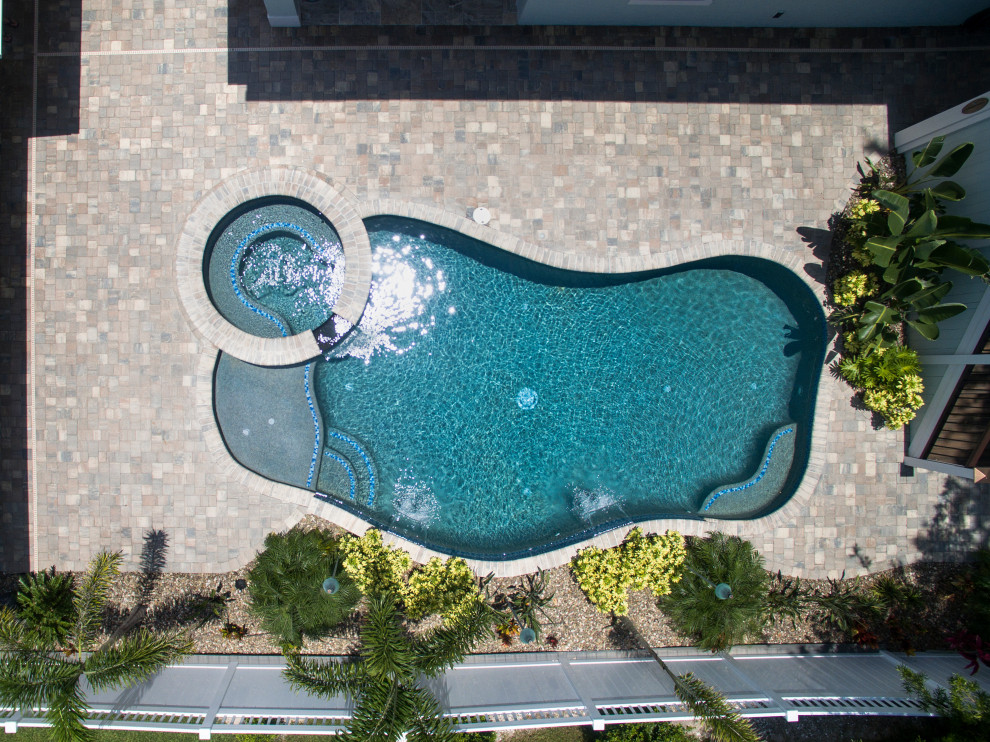 Esempio di una piscina tropicale personalizzata con una vasca idromassaggio