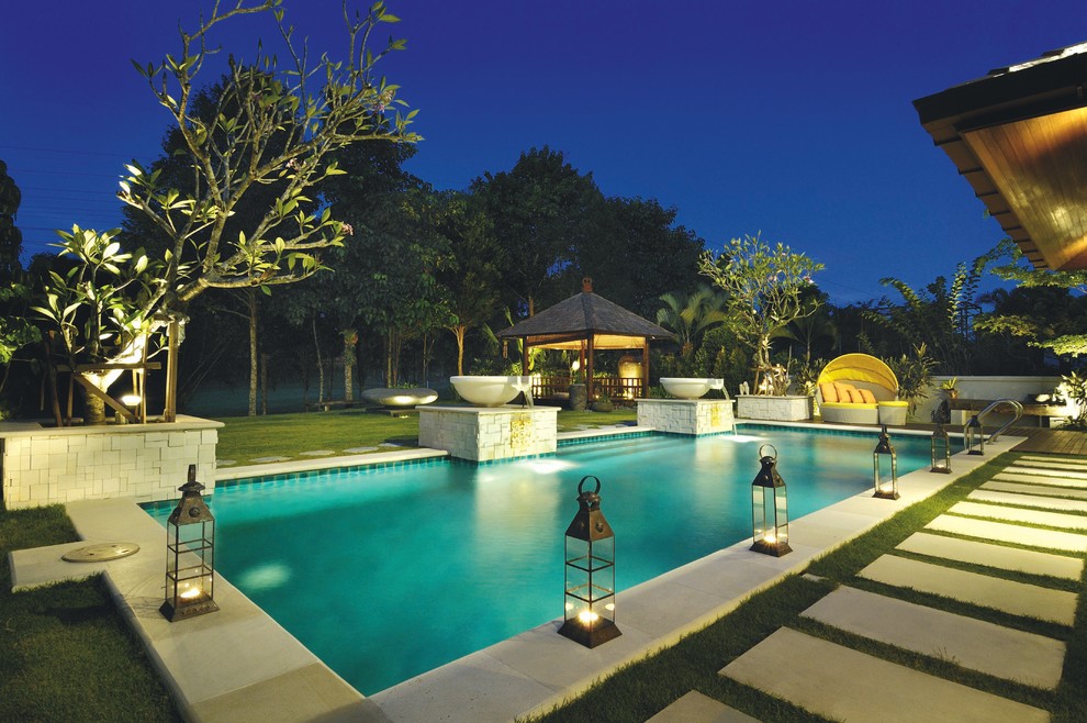 Imagen de piscina tropical rectangular con adoquines de hormigón