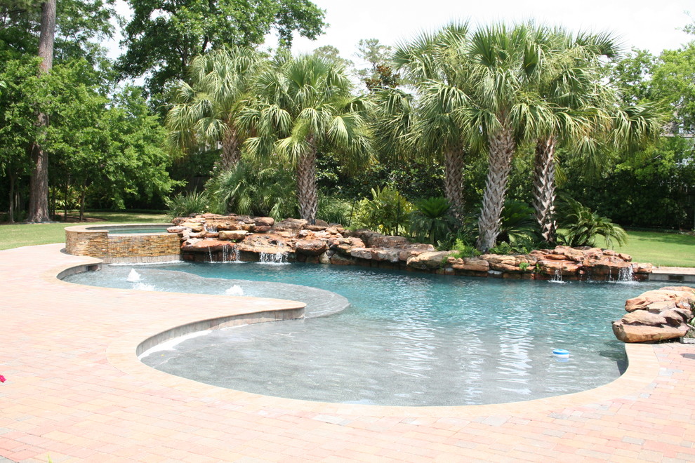 Modelo de piscinas y jacuzzis naturales tropicales grandes a medida en patio trasero con adoquines de ladrillo