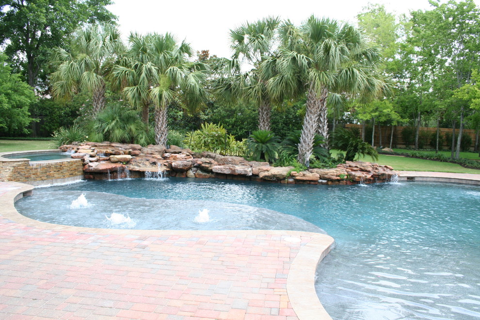 Diseño de piscinas y jacuzzis naturales tropicales grandes a medida en patio trasero con adoquines de ladrillo