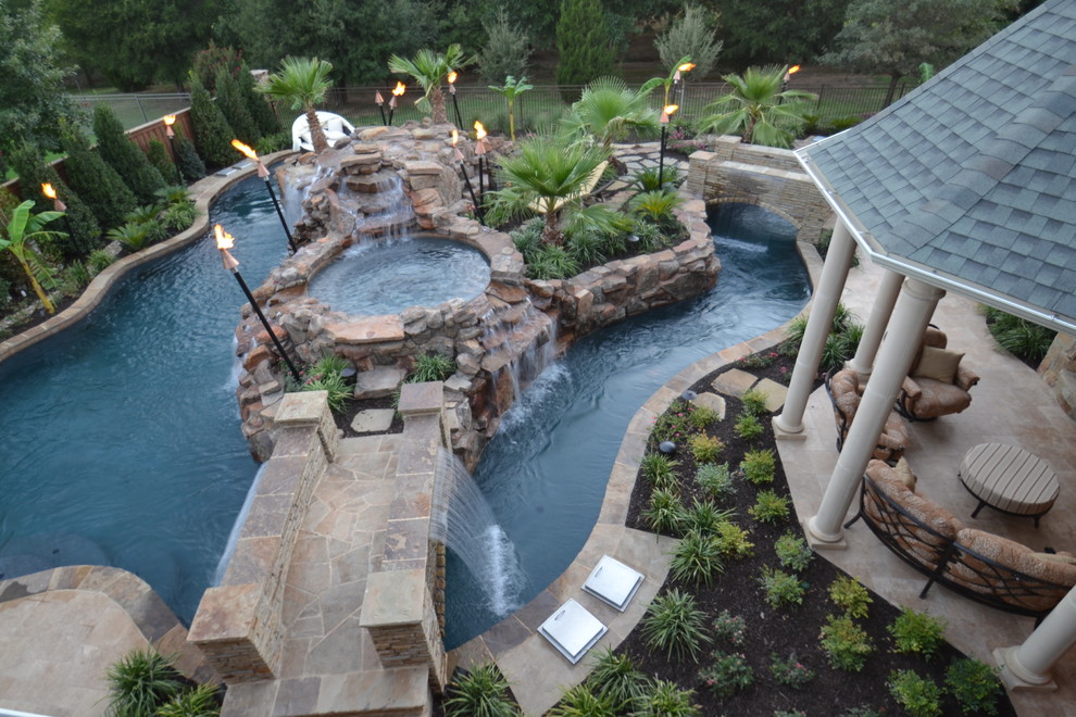 Large island style backyard stone and custom-shaped natural pool fountain photo in Dallas