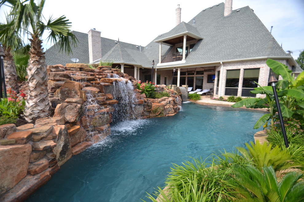 Inspiration pour une grande piscine naturelle et arrière ethnique sur mesure avec un point d'eau et des pavés en pierre naturelle.
