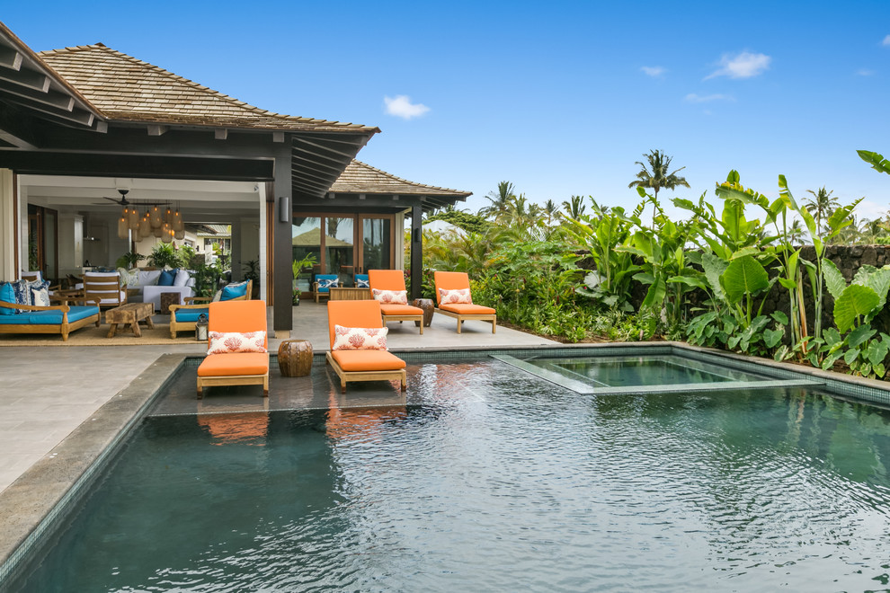 Foto di una piscina tropicale rettangolare di medie dimensioni e dietro casa con una vasca idromassaggio e piastrelle
