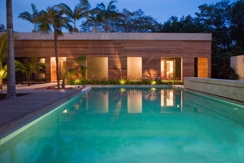 Cette image montre une grande piscine ethnique rectangle avec une terrasse en bois.