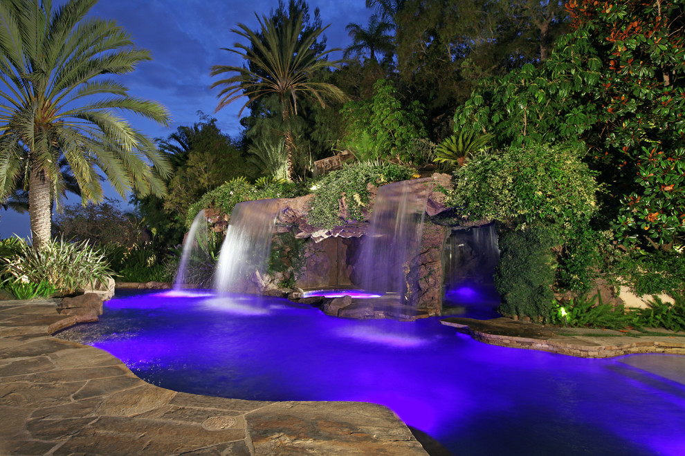 Ispirazione per una piscina naturale tropicale personalizzata con pavimentazioni in pietra naturale e fontane