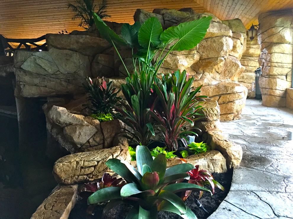 Bild på en mellanstor tropisk anpassad träningspool på baksidan av huset, med en fontän och naturstensplattor