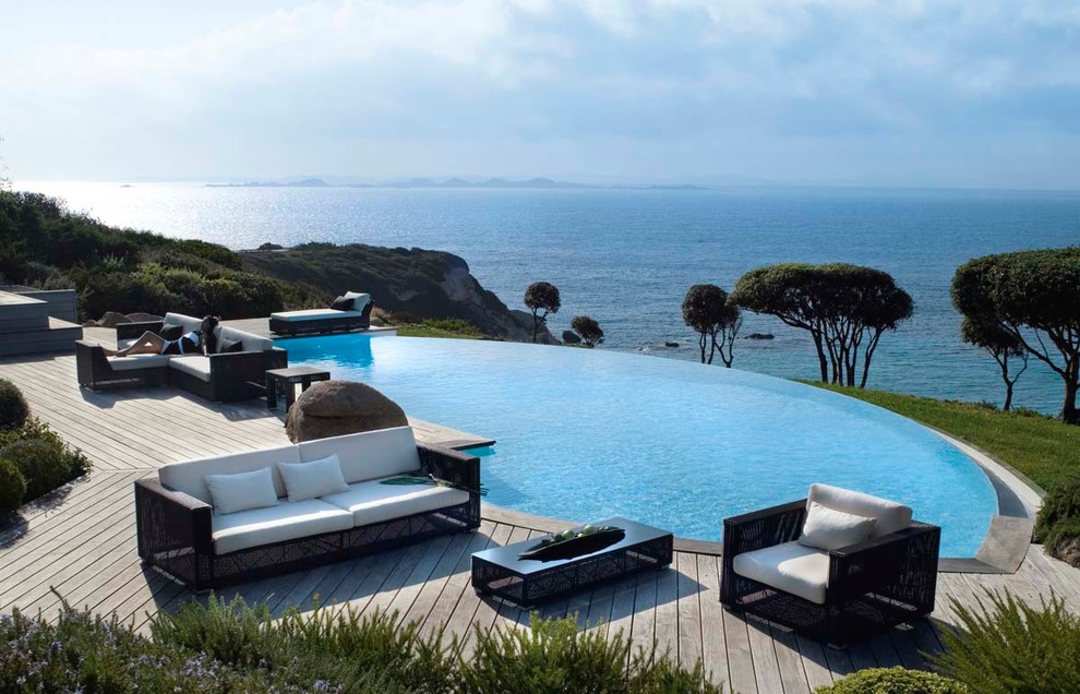 Diseño de piscina infinita exótica de tamaño medio a medida en patio trasero con entablado