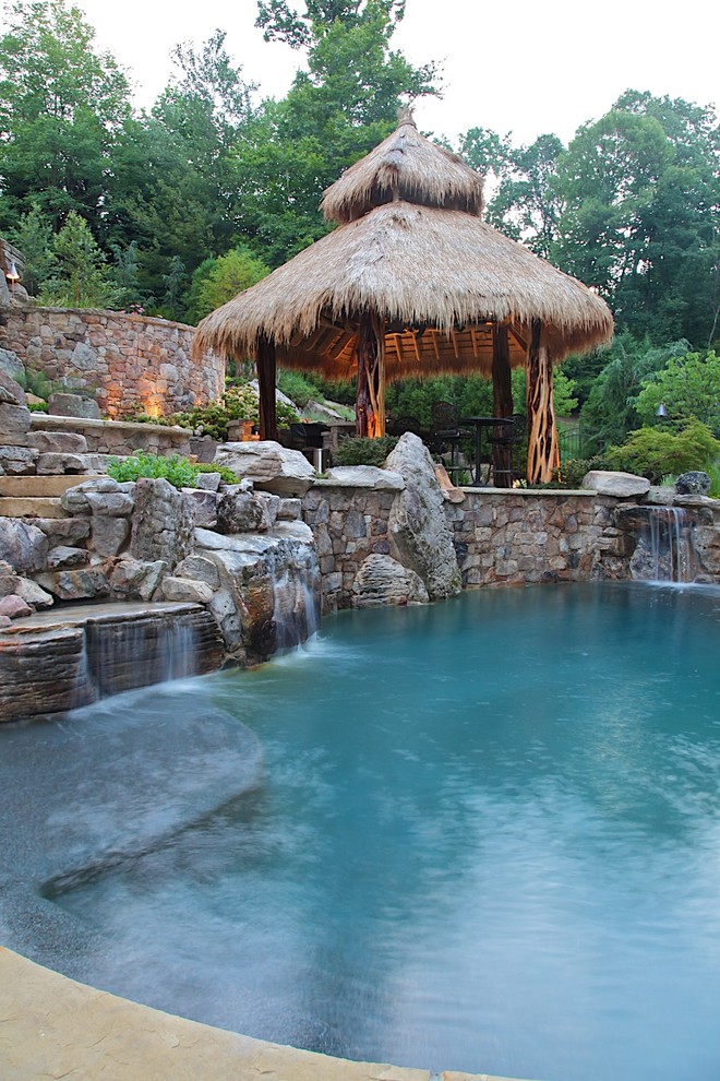 На фото: большой бассейн на заднем дворе в морском стиле с фонтаном