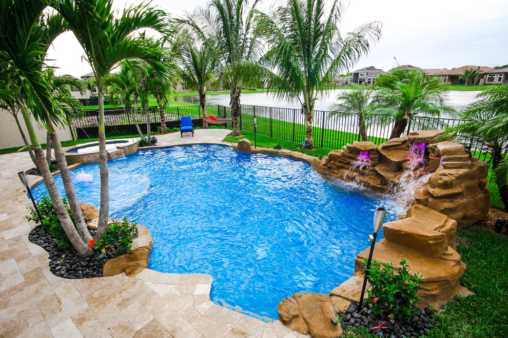 Großer Pool hinter dem Haus in individueller Form mit Wasserspiel und Natursteinplatten in Miami