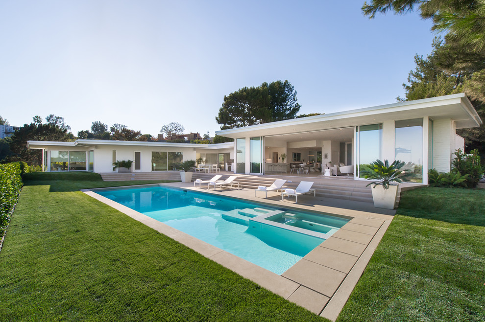 Стильный дизайн: большой прямоугольный бассейн на заднем дворе в стиле ретро с покрытием из бетонных плит - последний тренд