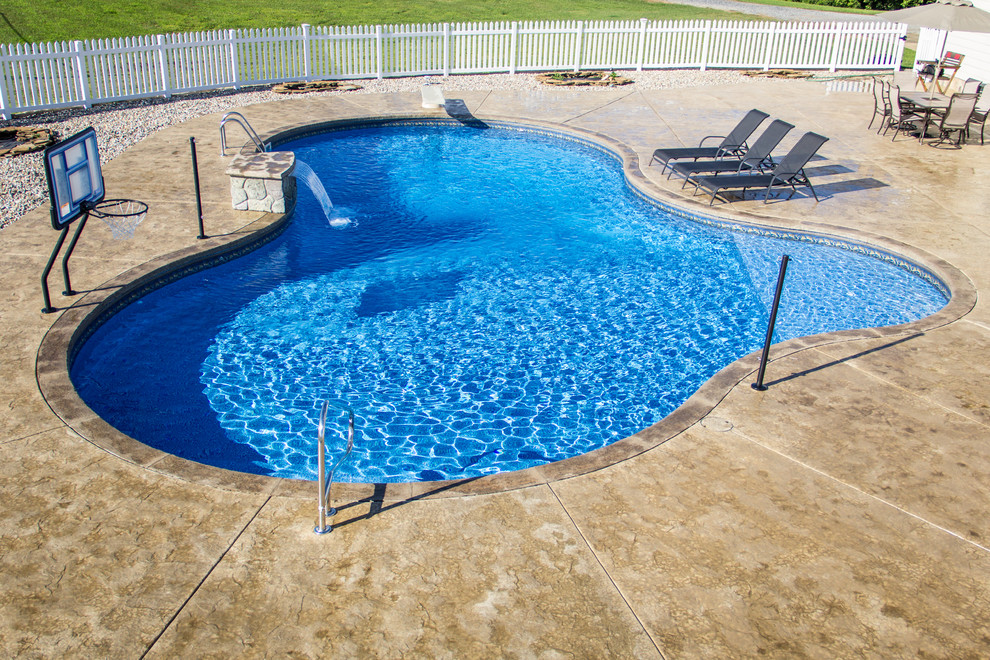 Imagen de piscina con fuente mediterránea grande a medida en patio trasero con suelo de hormigón estampado