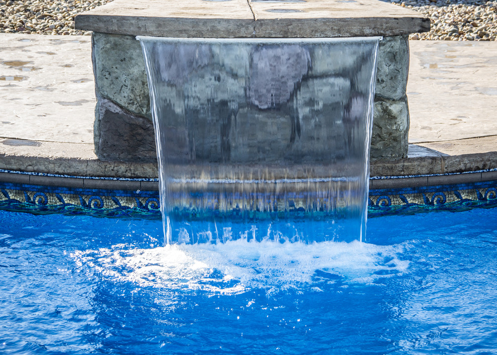 На фото: большой бассейн произвольной формы на заднем дворе в средиземноморском стиле с фонтаном и покрытием из декоративного бетона с