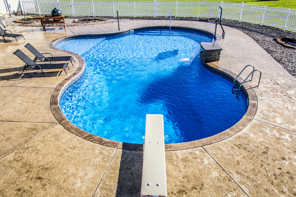 Diseño de piscina con fuente mediterránea grande a medida en patio trasero con suelo de hormigón estampado