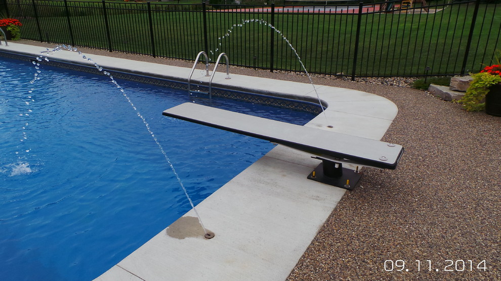 Immagine di una grande piscina design a "L" dietro casa con lastre di cemento