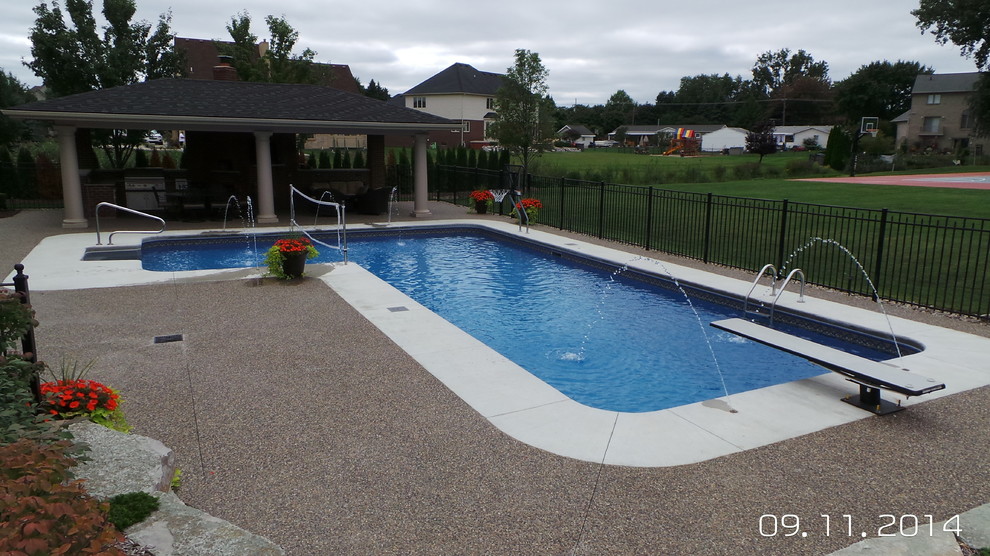 Foto de piscina grande en forma de L en patio trasero con losas de hormigón