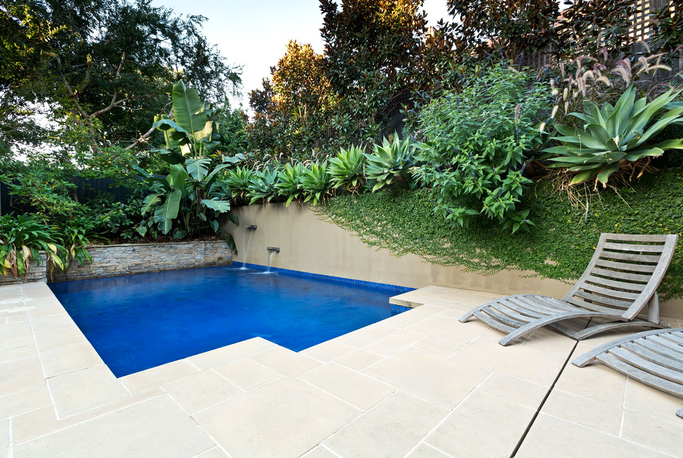 Esempio di una piscina tradizionale rettangolare di medie dimensioni e dietro casa con fontane e pavimentazioni in cemento