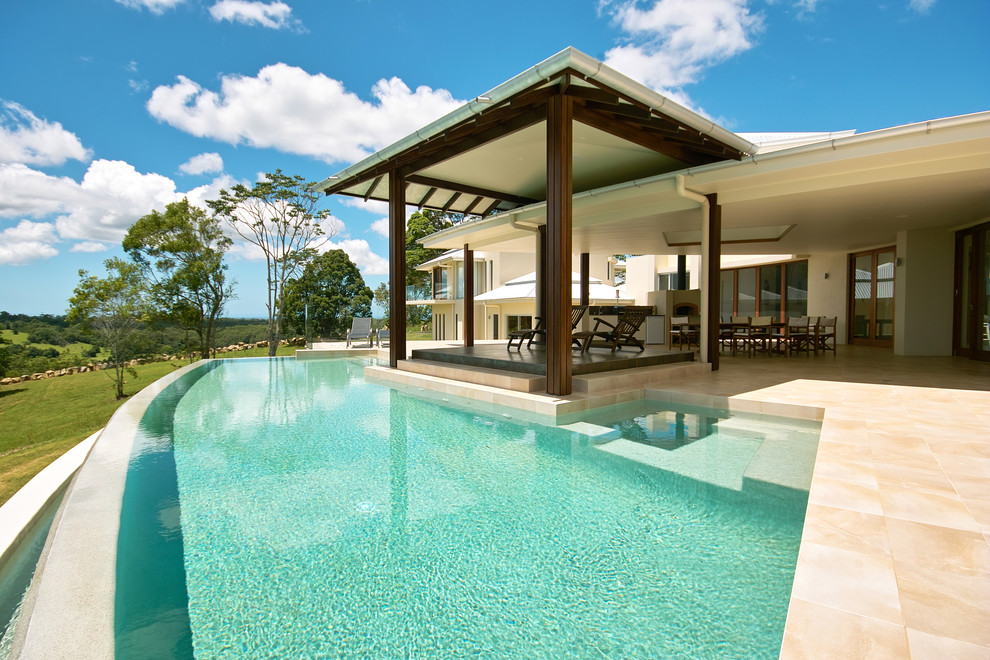 This is an example of a medium sized world-inspired back custom shaped infinity swimming pool in Brisbane.