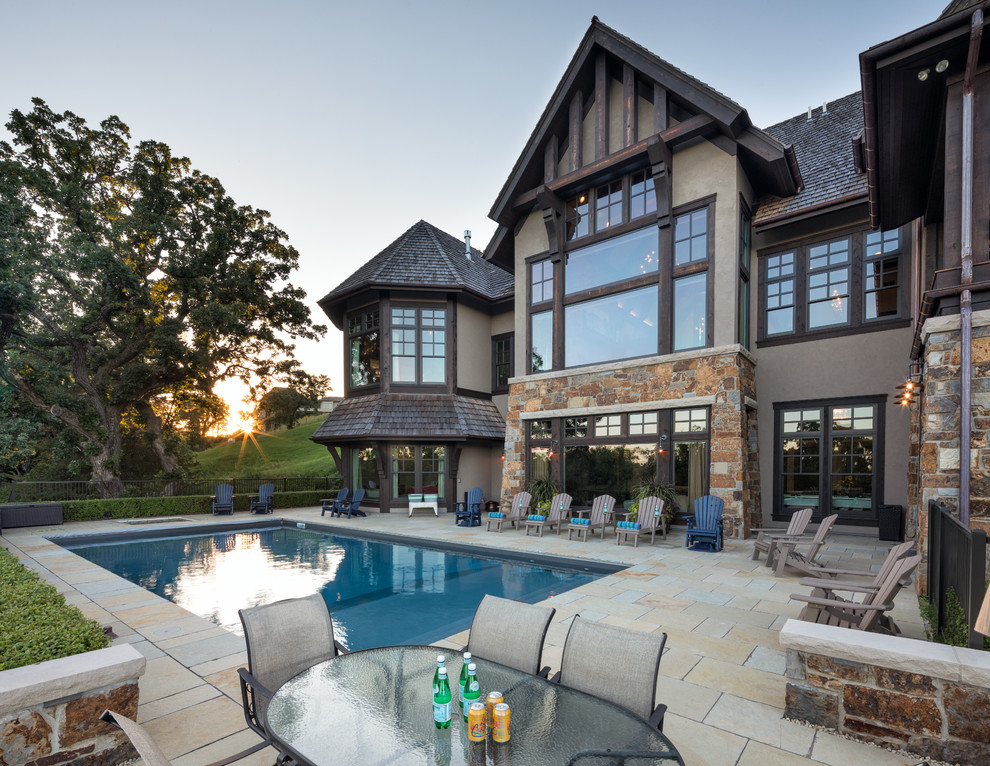 Ispirazione per una piscina monocorsia stile americano rettangolare dietro casa con una vasca idromassaggio e pavimentazioni in pietra naturale