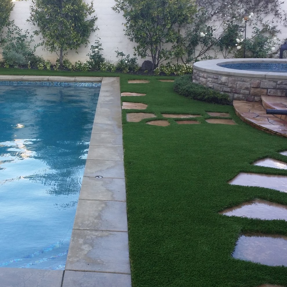 Immagine di una piscina monocorsia minimalista rettangolare di medie dimensioni e dietro casa con pavimentazioni in pietra naturale e una vasca idromassaggio