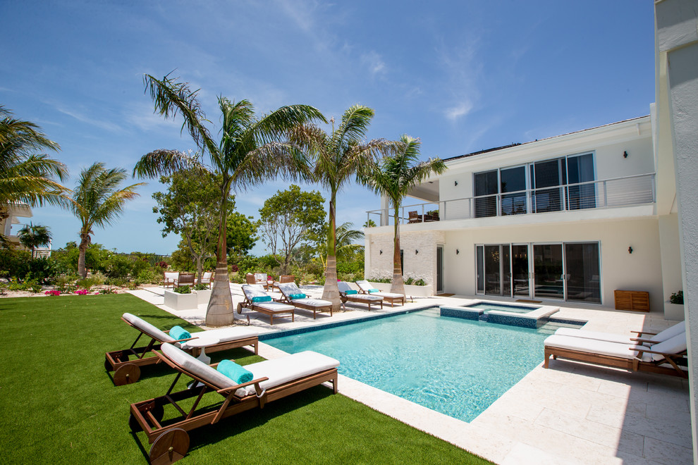 Ejemplo de piscinas y jacuzzis alargados costeros extra grandes rectangulares en patio trasero con adoquines de piedra natural