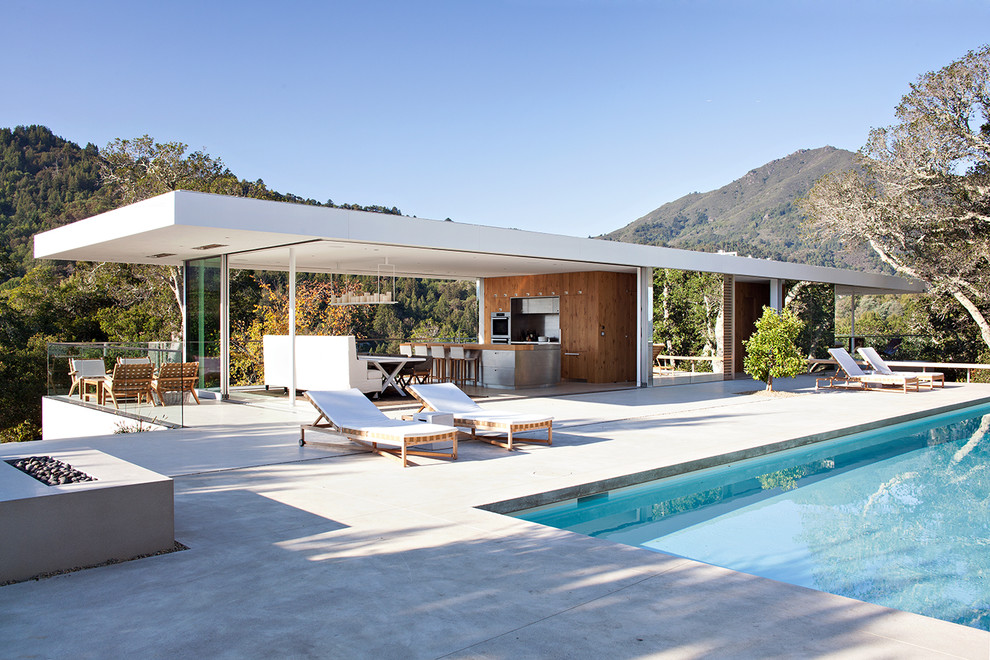 Photo of a modern rectangular swimming pool in San Francisco with a pool house and concrete slabs.
