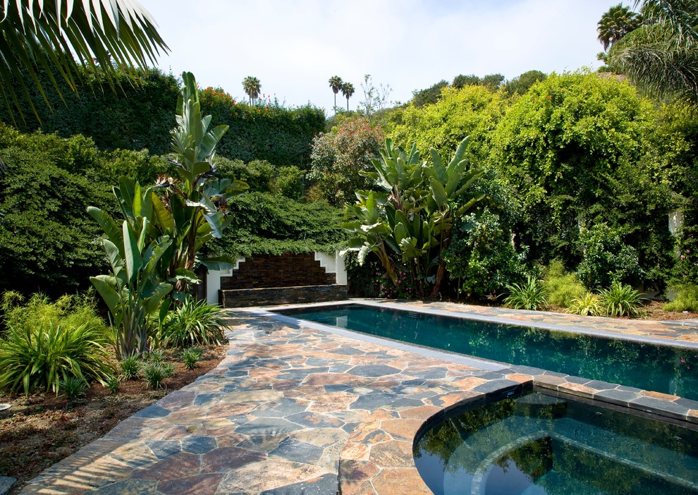 Foto de piscinas y jacuzzis alargados tropicales grandes rectangulares en patio trasero con adoquines de piedra natural