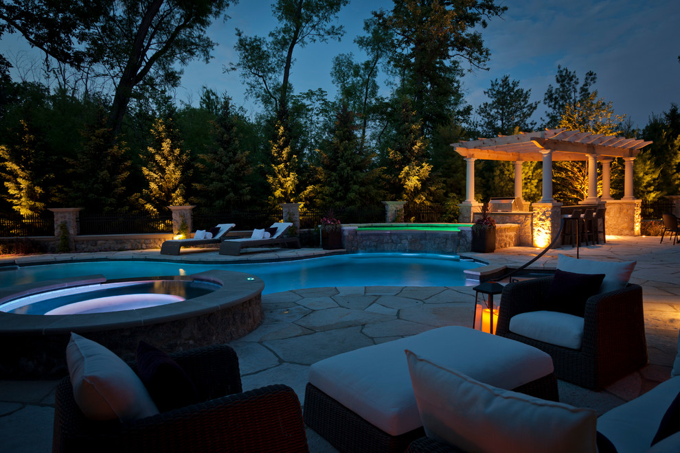 Ejemplo de piscina con fuente clásica renovada grande a medida en patio trasero con adoquines de piedra natural
