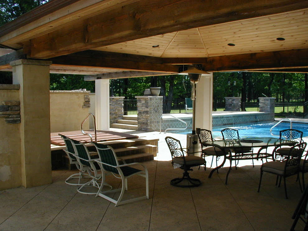 Diseño de piscina con fuente mediterránea grande rectangular en patio trasero con losas de hormigón