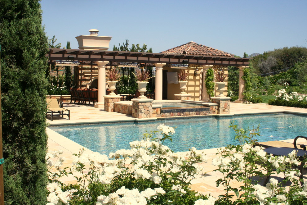 На фото: большой бассейн на заднем дворе в средиземноморском стиле с покрытием из каменной брусчатки с