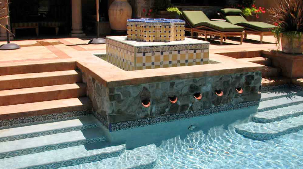 Esempio di un'ampia piscina naturale mediterranea personalizzata dietro casa con fontane e lastre di cemento