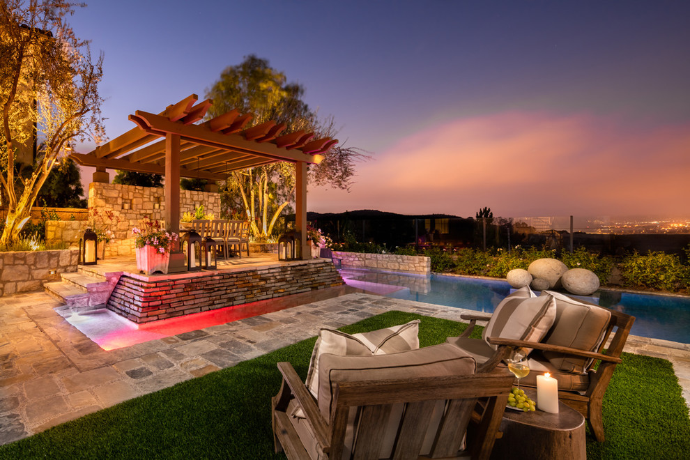 Ejemplo de piscina mediterránea de tamaño medio rectangular en patio trasero con adoquines de piedra natural