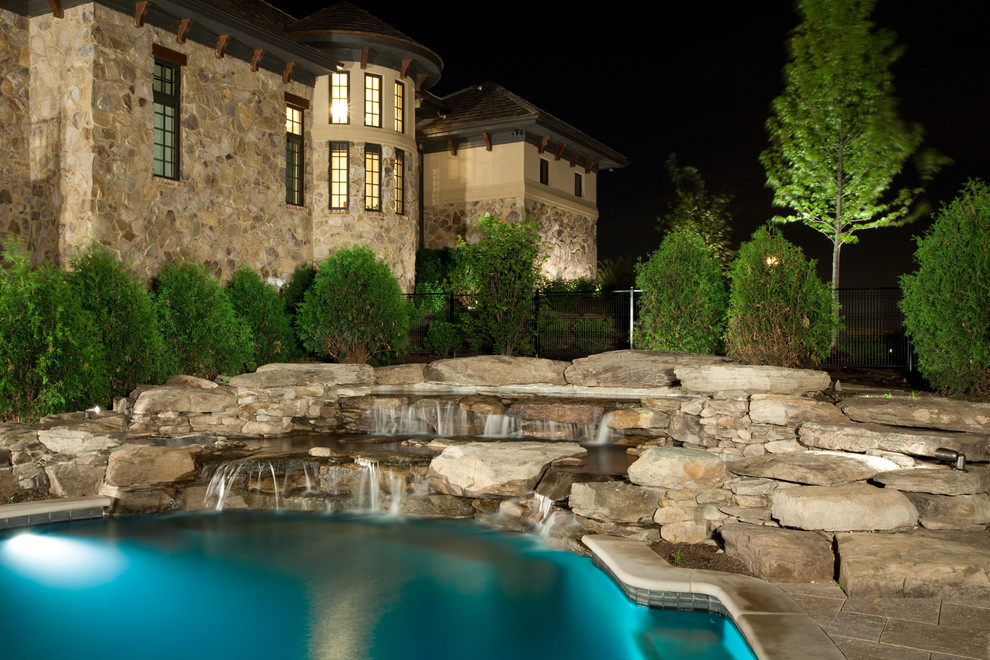 Foto de piscina con fuente bohemia grande a medida en patio trasero con adoquines de piedra natural