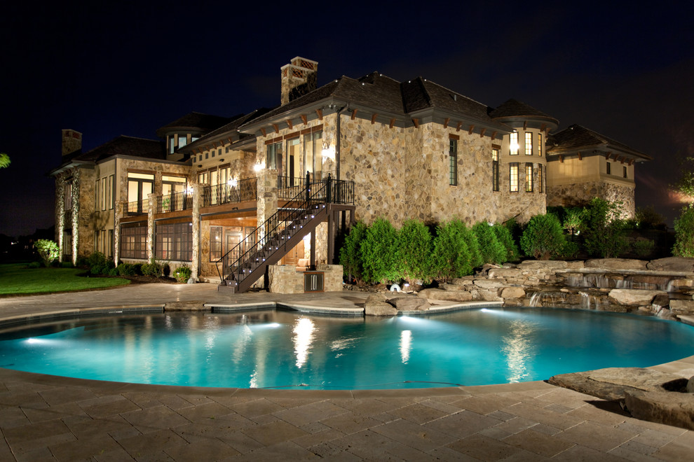 Immagine di una grande piscina bohémian personalizzata dietro casa con fontane e pavimentazioni in pietra naturale