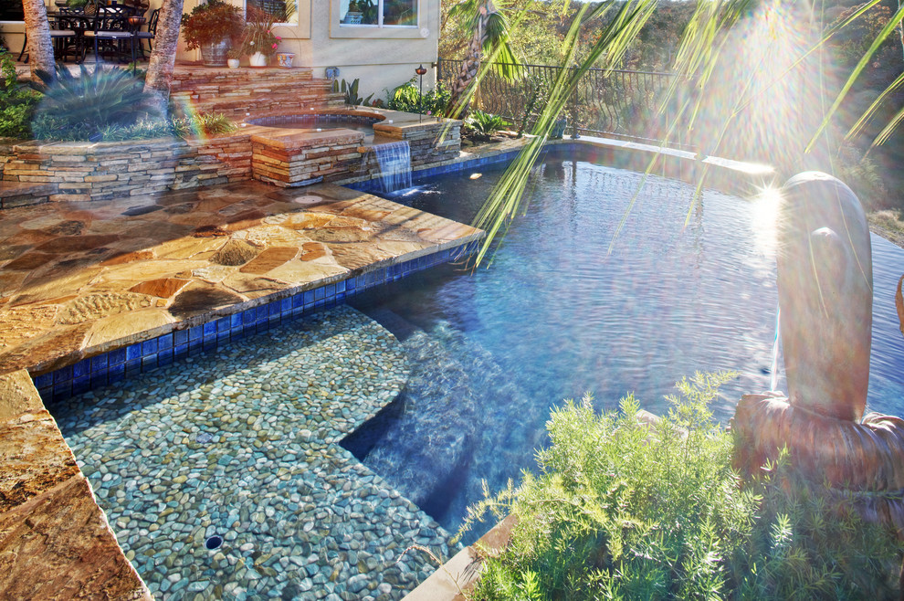 Hot tub - large mediterranean backyard stone and custom-shaped infinity hot tub idea in Austin