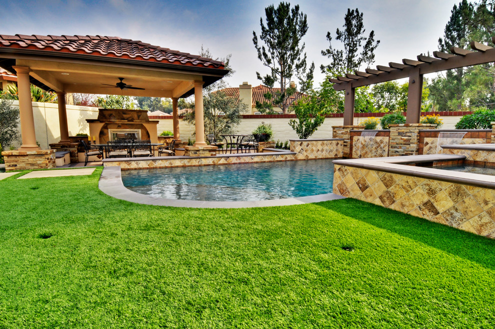 This is an example of a medium sized mediterranean back rectangular above ground swimming pool in Orange County with a water feature and concrete slabs.