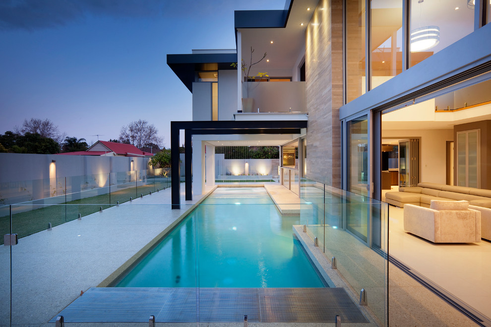 Diseño de piscina actual rectangular en patio trasero con losas de hormigón