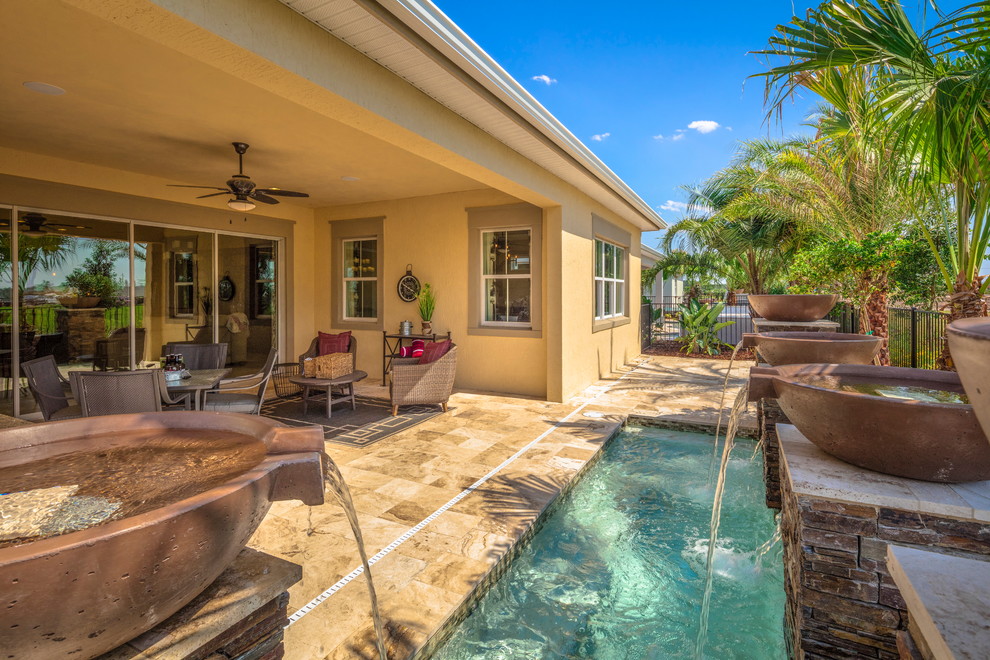 Kleiner Mediterraner Pool hinter dem Haus in rechteckiger Form mit Wasserspiel und Natursteinplatten in Orlando