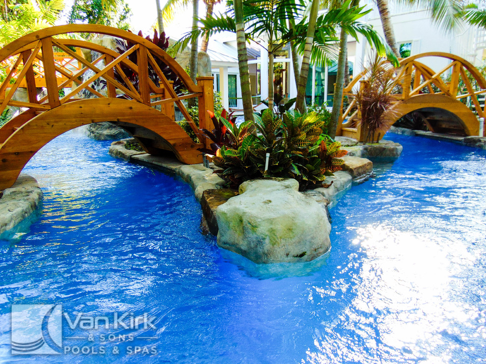 Ispirazione per un'ampia piscina naturale tropicale personalizzata dietro casa con fontane e pavimentazioni in pietra naturale