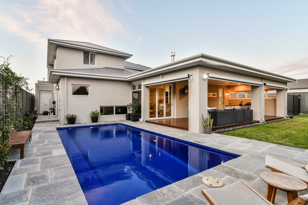 Esempio di una piscina monocorsia minimalista rettangolare di medie dimensioni e dietro casa con pavimentazioni in pietra naturale