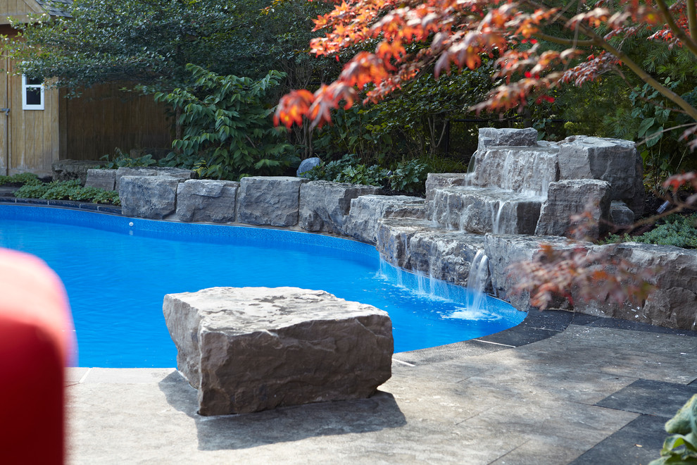 Esempio di una grande piscina naturale contemporanea personalizzata dietro casa con fontane e cemento stampato