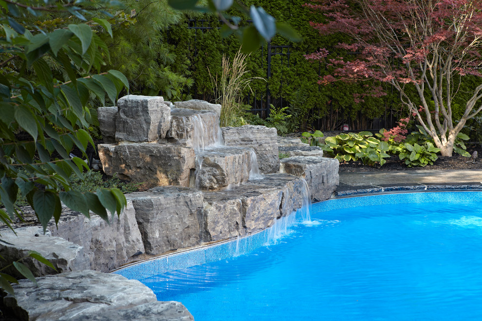 Inspiration for a large contemporary back custom shaped natural swimming pool in Toronto with a water feature and stamped concrete.