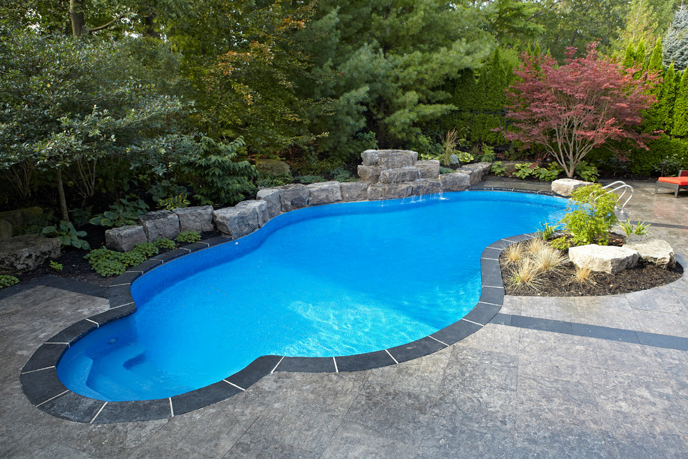 Ispirazione per una grande piscina naturale minimal personalizzata dietro casa con fontane e cemento stampato