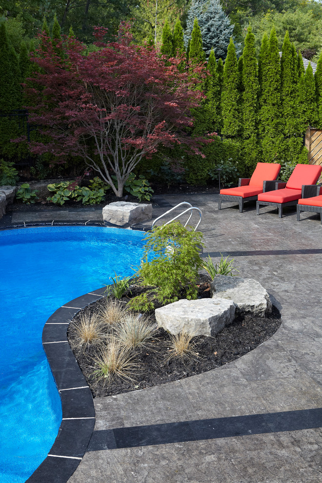 Large trendy backyard stamped concrete and custom-shaped natural pool fountain photo in Toronto