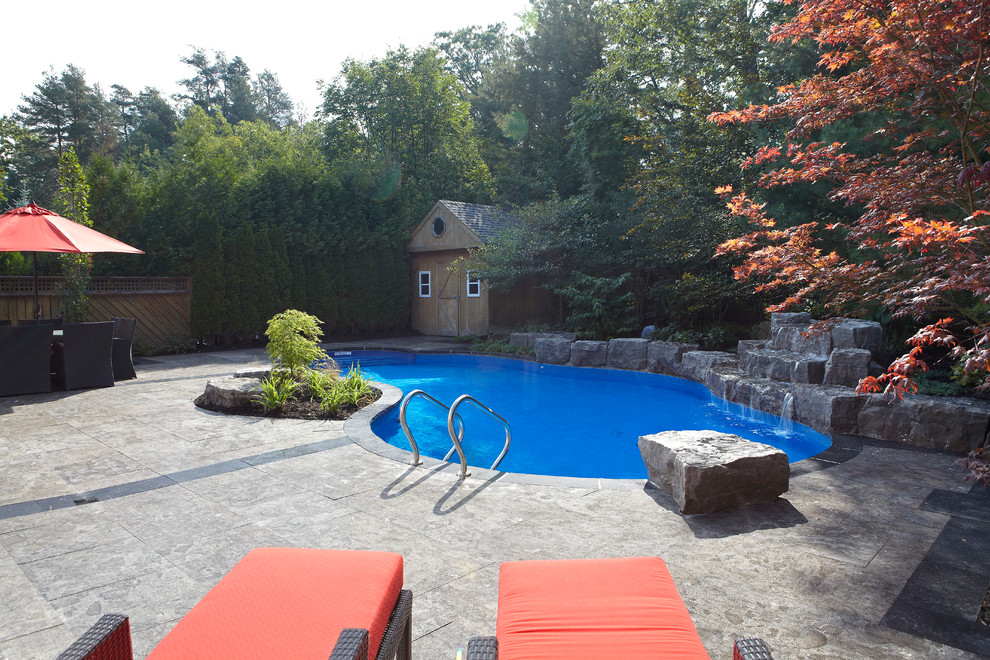 Foto di una grande piscina naturale design personalizzata dietro casa con fontane e cemento stampato
