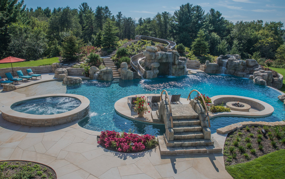 This is an example of a large traditional custom shaped swimming pool in Chicago with a water slide and natural stone paving.