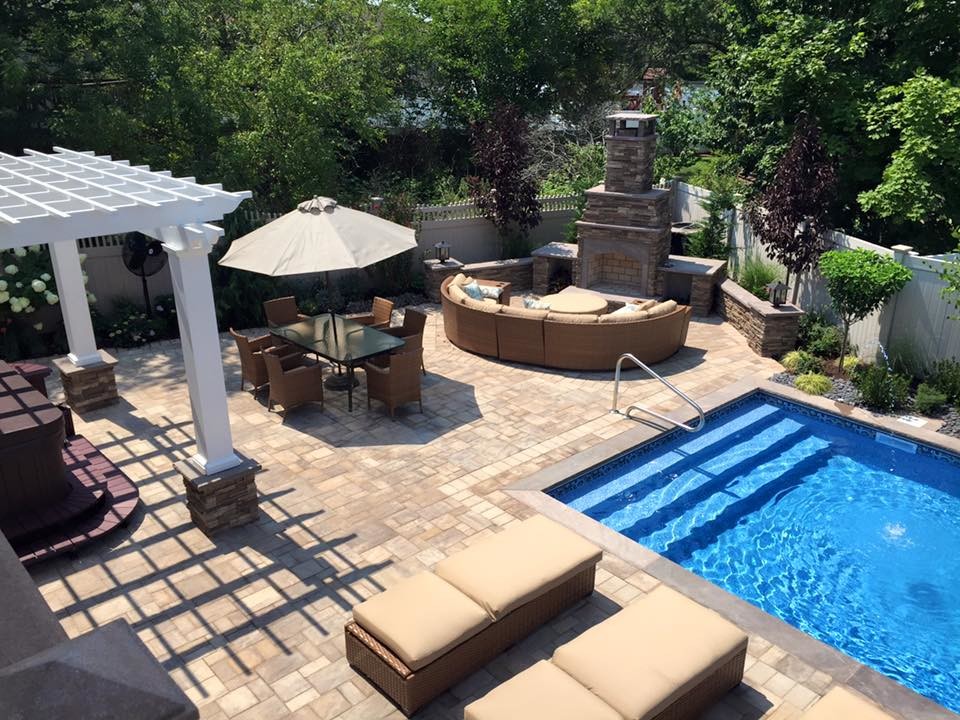 Imagen de piscina tradicional grande rectangular en patio trasero con adoquines de hormigón