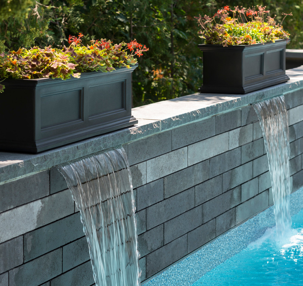 Ispirazione per una piscina minimalista rettangolare dietro casa con fontane e pavimentazioni in cemento