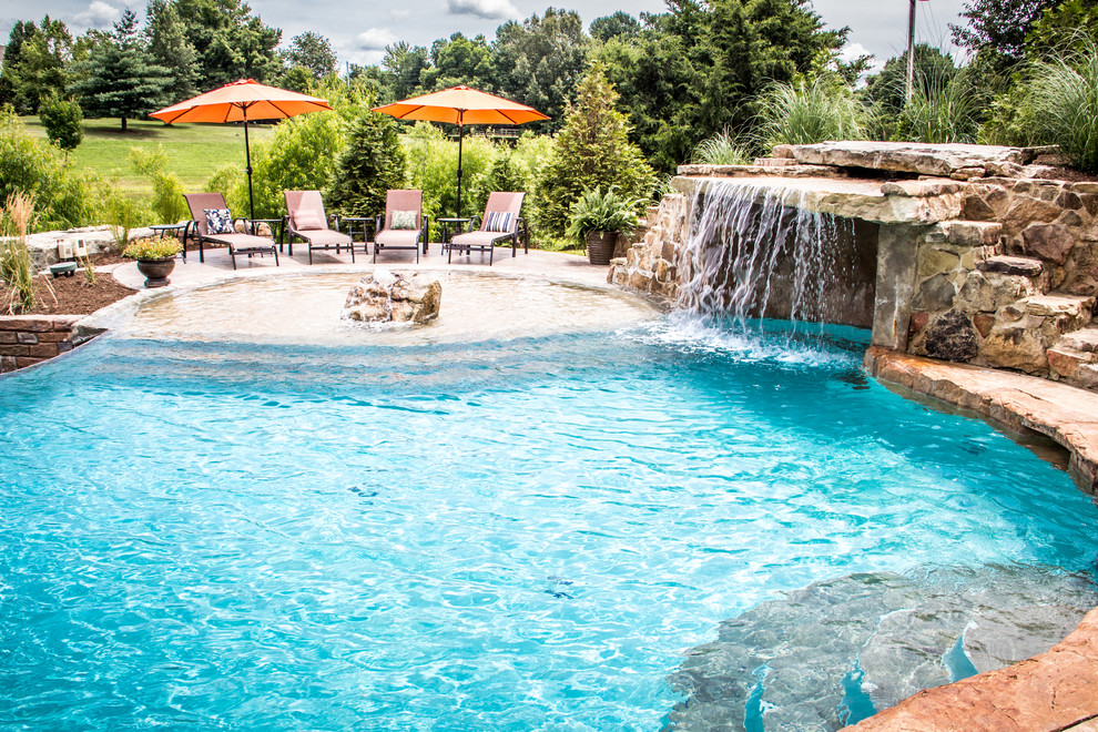 Foto de piscina con fuente natural exótica grande a medida en patio trasero con suelo de hormigón estampado