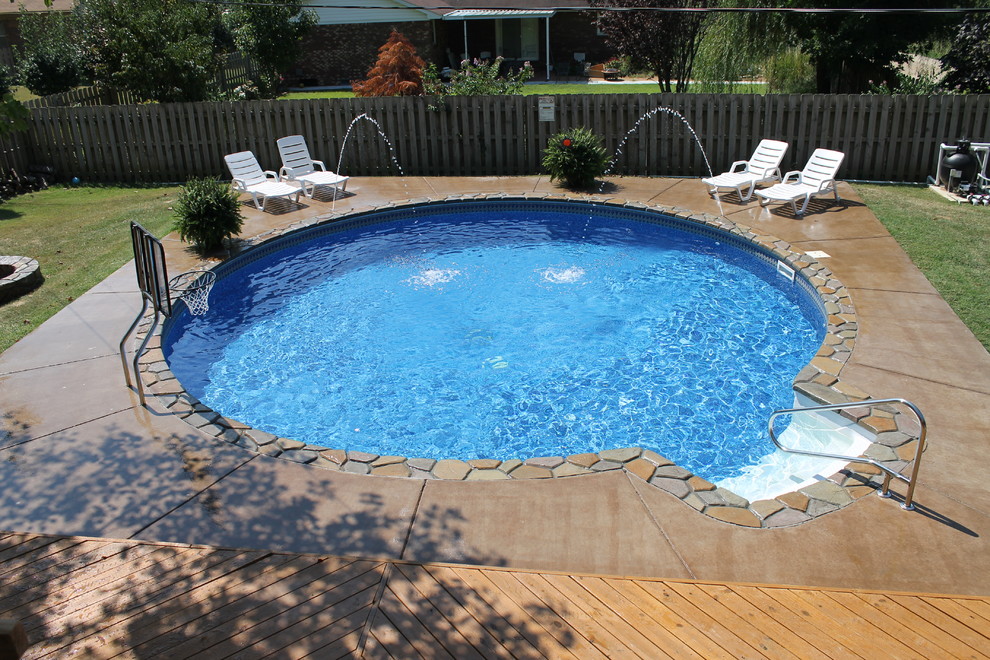 Diseño de piscina contemporánea de tamaño medio redondeada en patio trasero con losas de hormigón