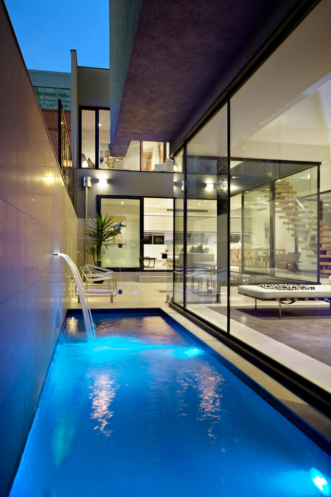 Esempio di una piscina monocorsia design rettangolare di medie dimensioni e dietro casa con fontane